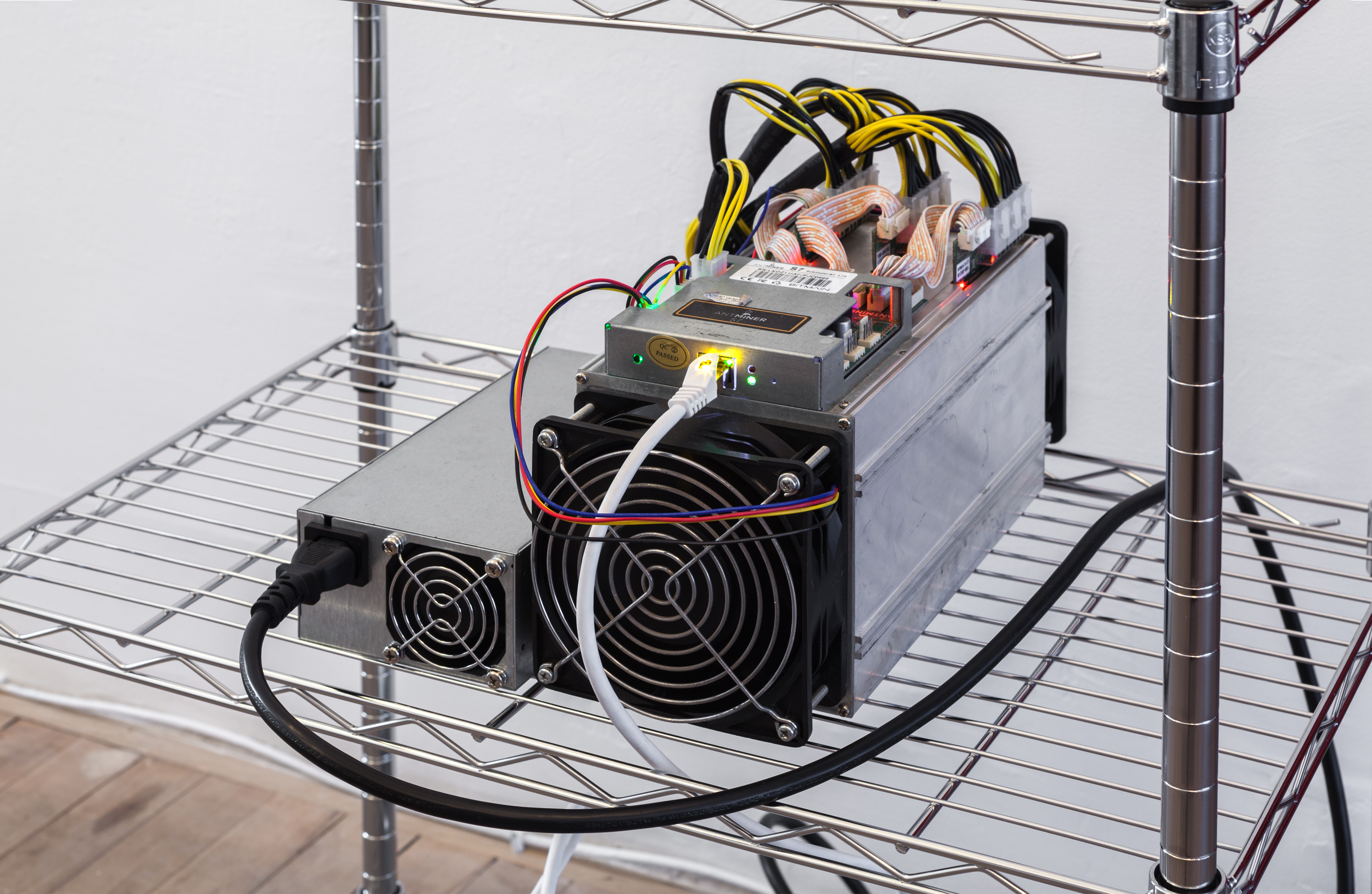 A device with several electrical wire connections is displayed on a metal wire shelf.