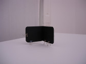 An open black wallet supported upright on a white surface by four binder clips attached to its left side and bottom edge.