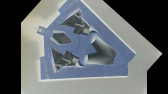 Negative film image that has been mirrored across a diagonal line of symmetry, depicting a blue board with objects arranged on it to create vaguely recognizable patterns.