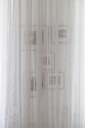 A white translucent chiffon curtain cascades over a set of five framed images mounted on a wall.