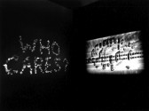A black and white photograph of two projected images emerging from darkness.