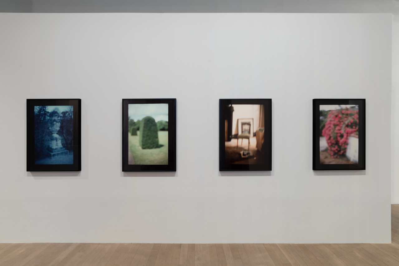 Four photographs, each with a monochromatic haze and black borders, hang in a line.