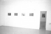Photographs hanging on walls in a gallery space with a doorway on the right.