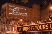 A view of Chinatown at night, with a projection onto a side of the building that reads, in handwritten text, 