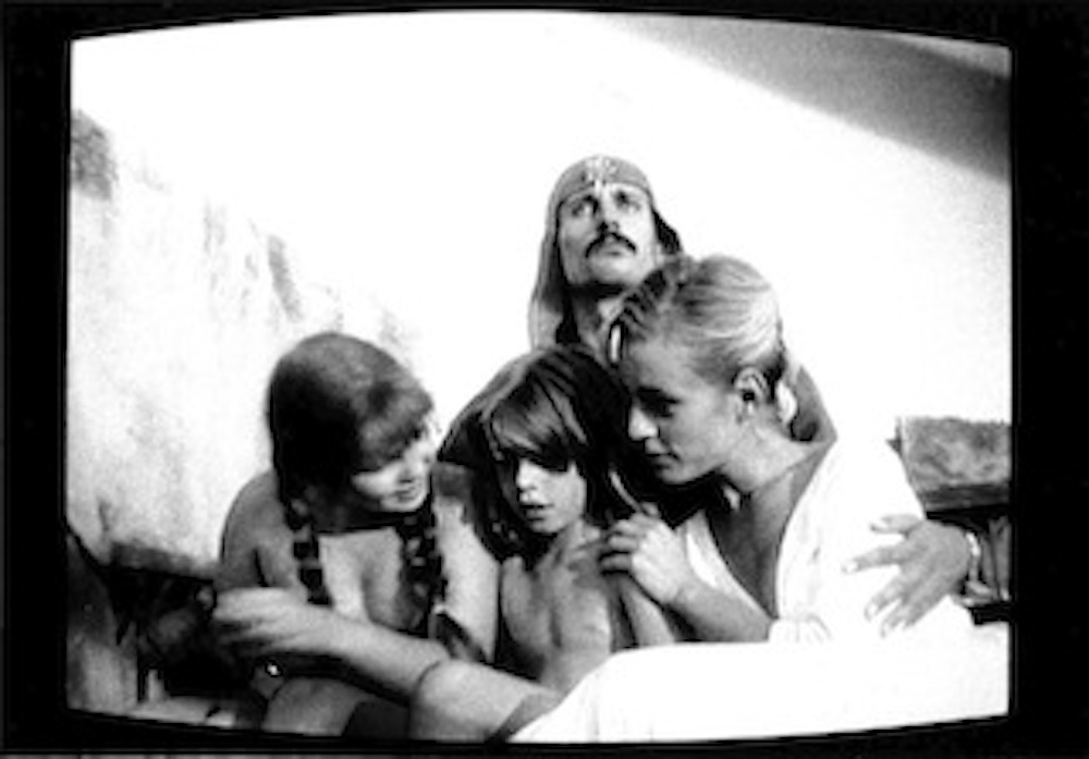 A seated group of four people cluster together in front of a white background.