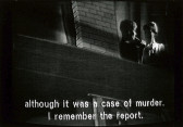Two people are seen from below, standing and facing one another in a shadowy window.  Below them, the subtitle text reads, 