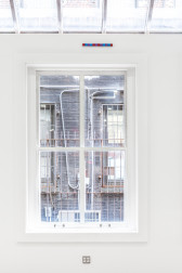 A small strip of pixeled colors is displayed left of center above a large window looking out onto a building.