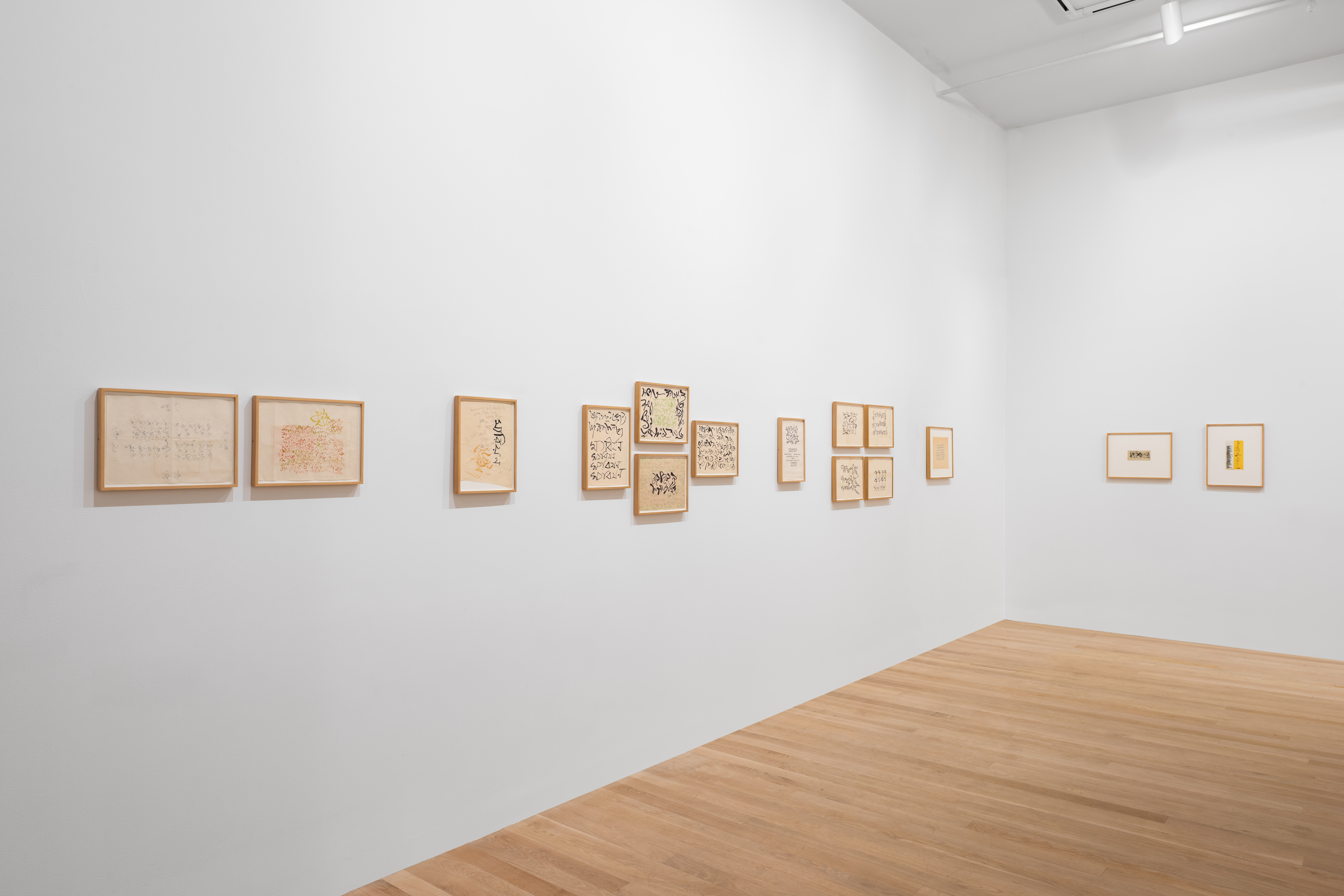 View of various framed works on paper on white gallery walls featuring abstract calligraphic strokes.