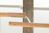A sharp image of two halves of a pvc pipe placed in front of an out of focus background. Water flows across the pipes; behind the pipes is a steel column.