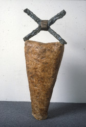 An inverted triangle of straw held together with wax supports an X made of lead.