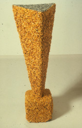 A cube supports an inverted pyramid, both covered in corn kernals, shown on a white background.