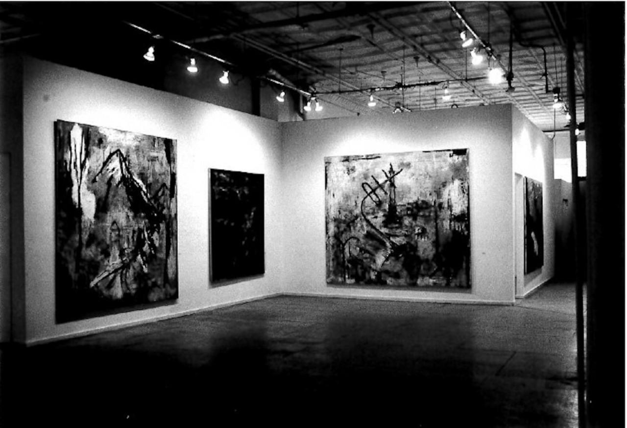 A few indistinguishable paintings appear on adjacent walls in a white-walled gallery space.