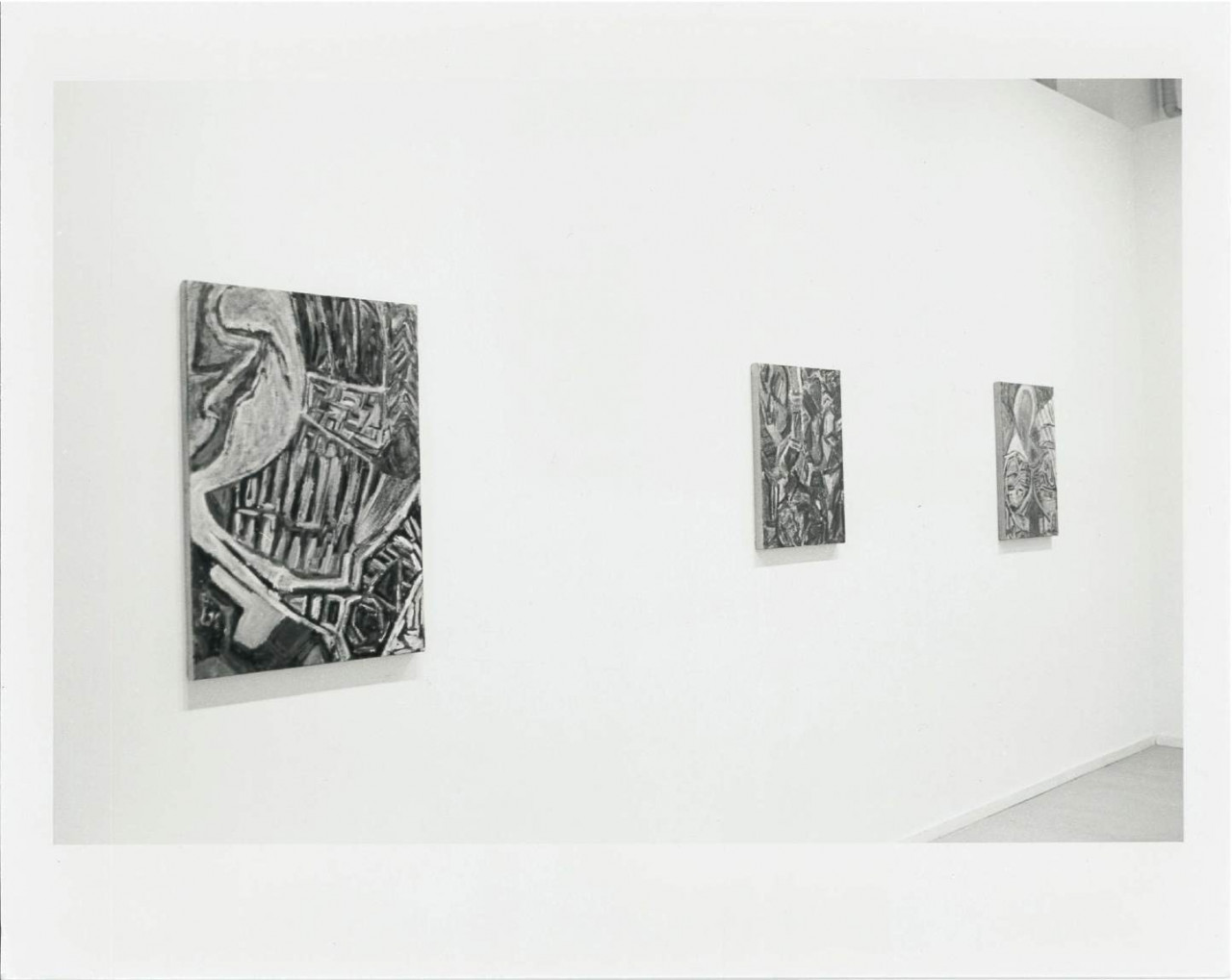 Figurative paintings are hanging on a wall in a white-walled gallery setting.