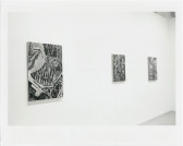 Figurative paintings are hanging on a wall in a white-walled gallery setting.