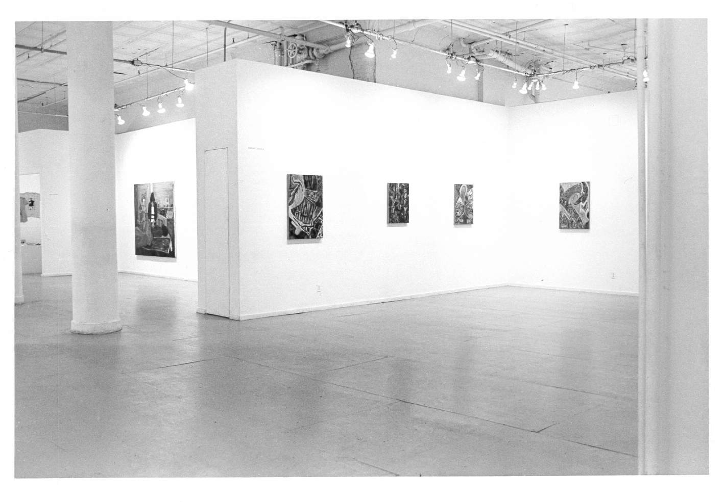 Paintings are visible hanging on walls in a white-walled gallery space with white columns in the background.
