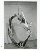 Circular bricolage sculpture in a white-walled gallery space.