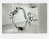 Circular sculptural forms hang from the ceiling and touch the floor in a white-walled gallery space.