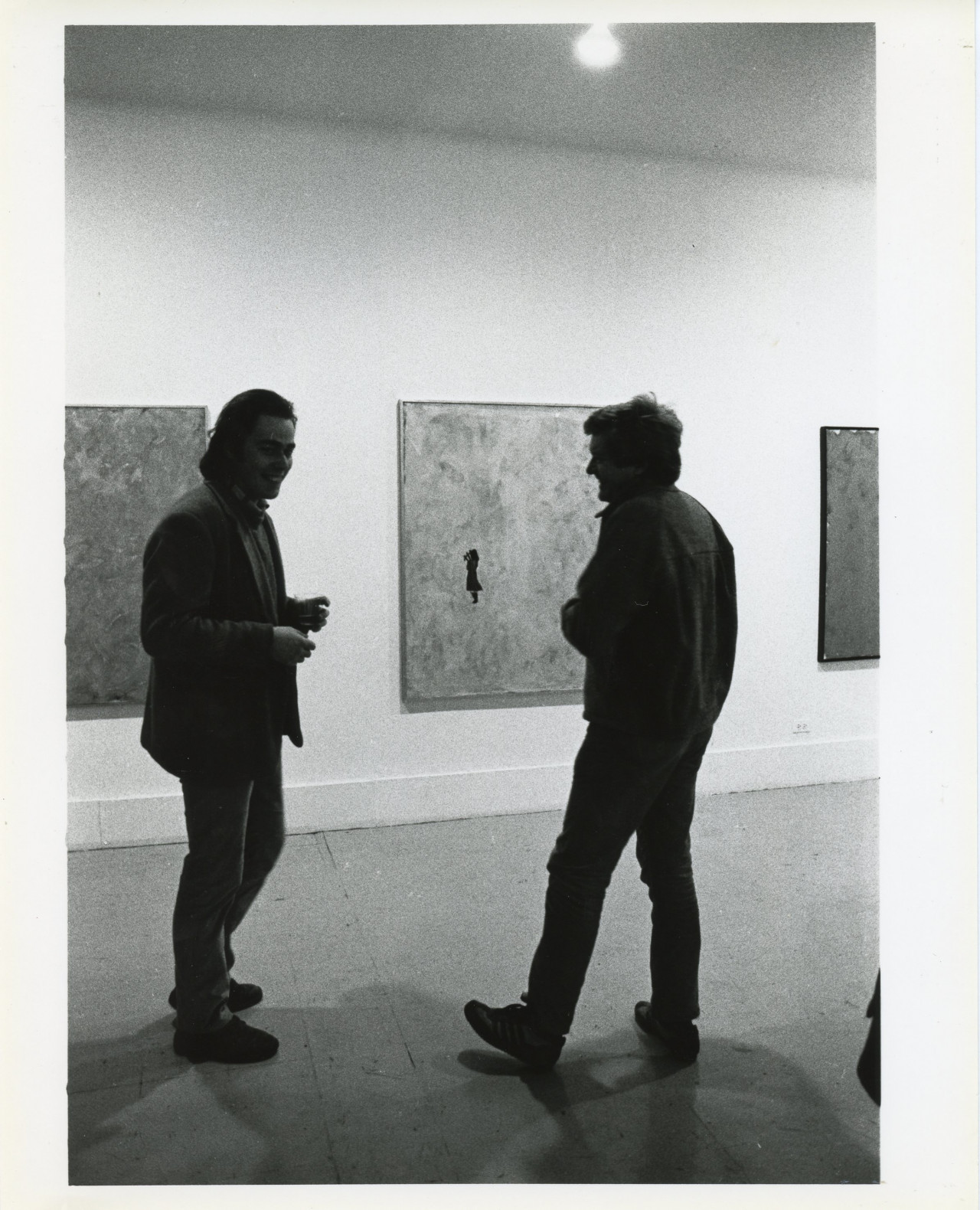 A photograph of the exhibition opening reception. A group of visitors look around at the art.