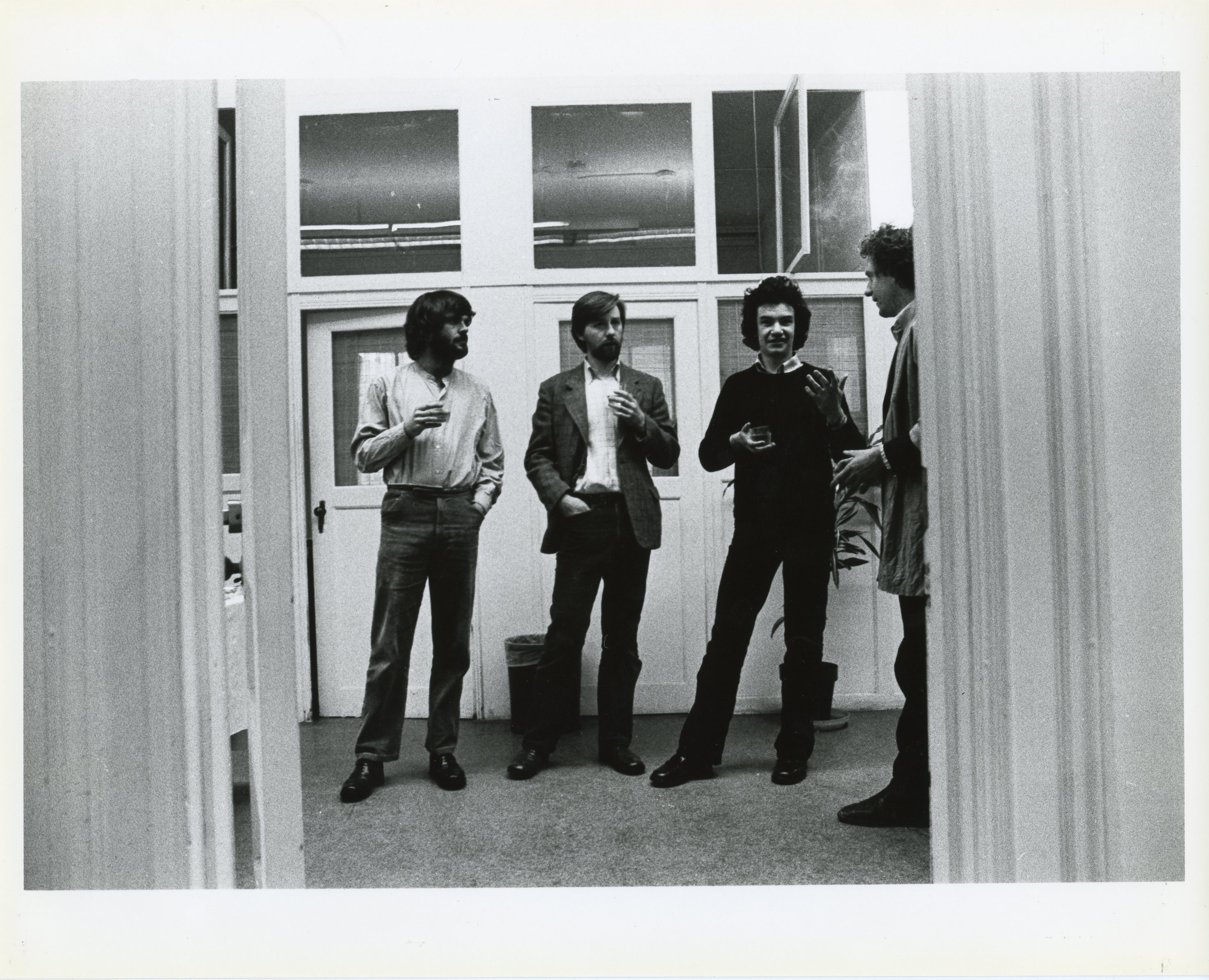 A photograph of the exhibition opening reception. A group of visitors look around at the art.