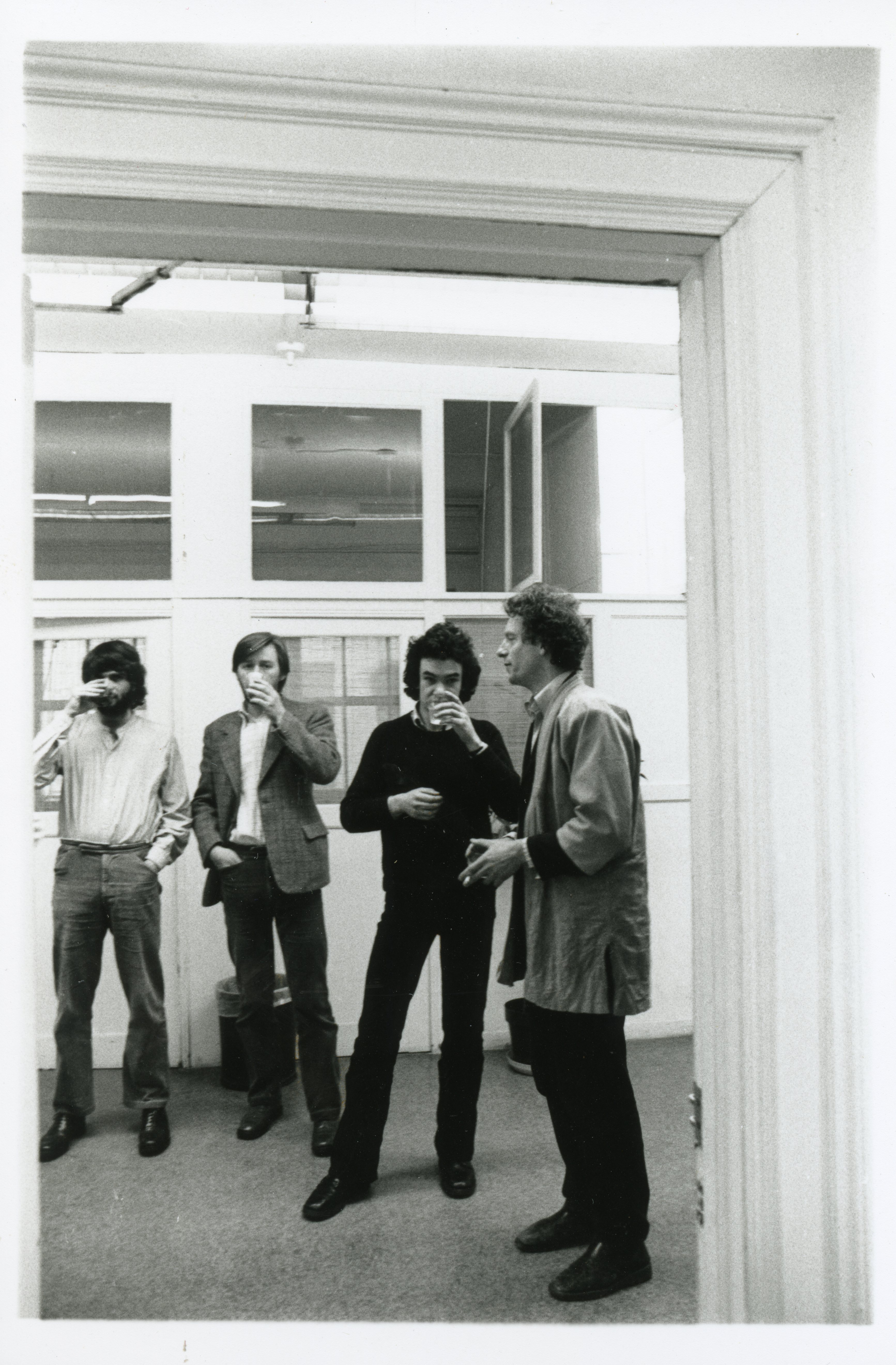A photograph of the exhibition opening reception. A group of visitors look around at the art.