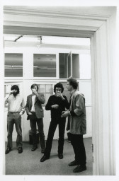 A photograph of the exhibition opening reception. A group of visitors look around at the art.