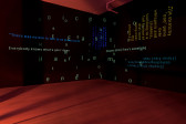 In a darkened room lit softly by red light, overlapping lines of open captions are projected on two adjacent black walls. The text varies in color (in faint greens, yellows and blues) and size.