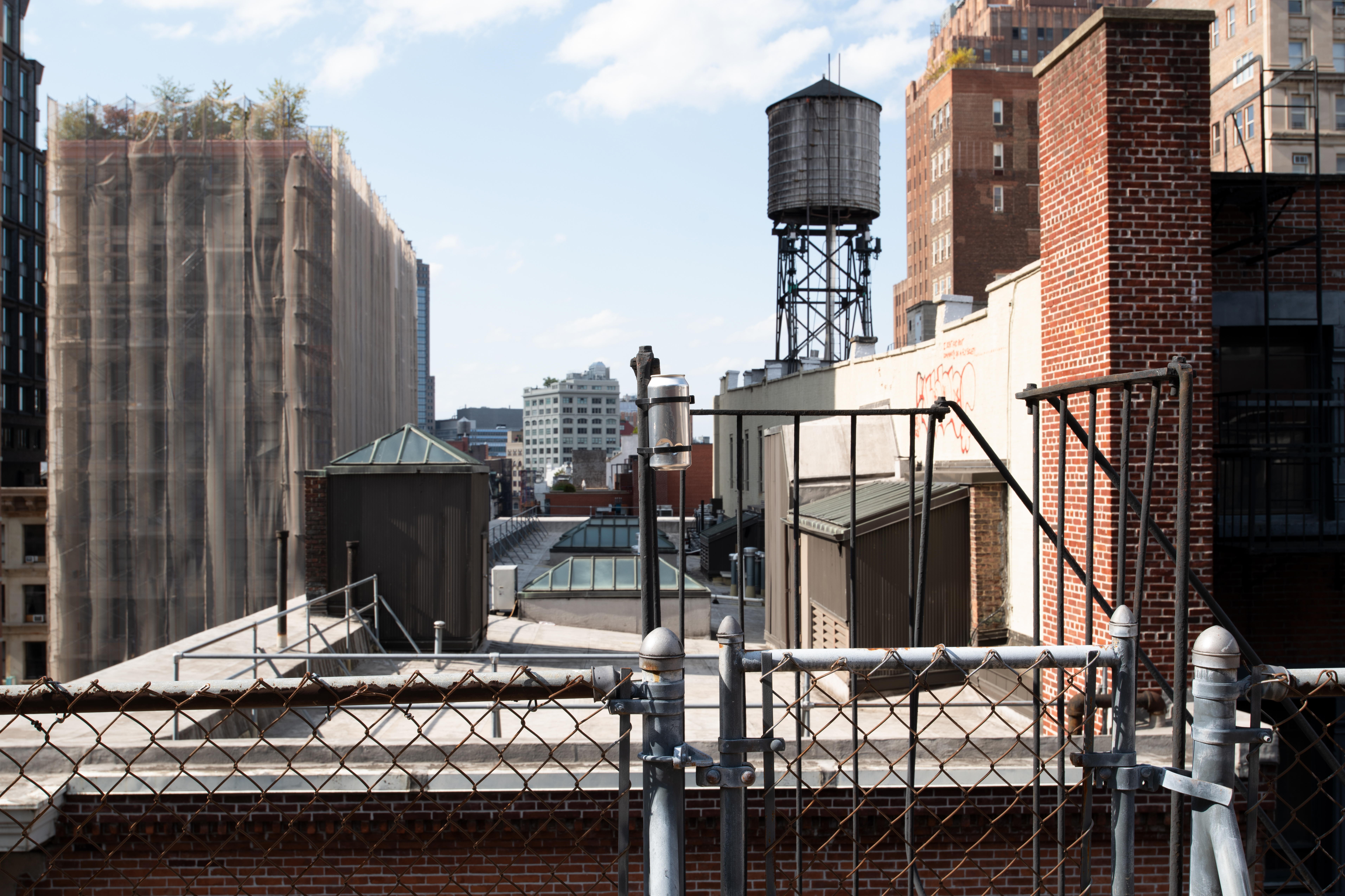 Against an urban landscape, a metal pinhole camera tin is mounted to a roof post.