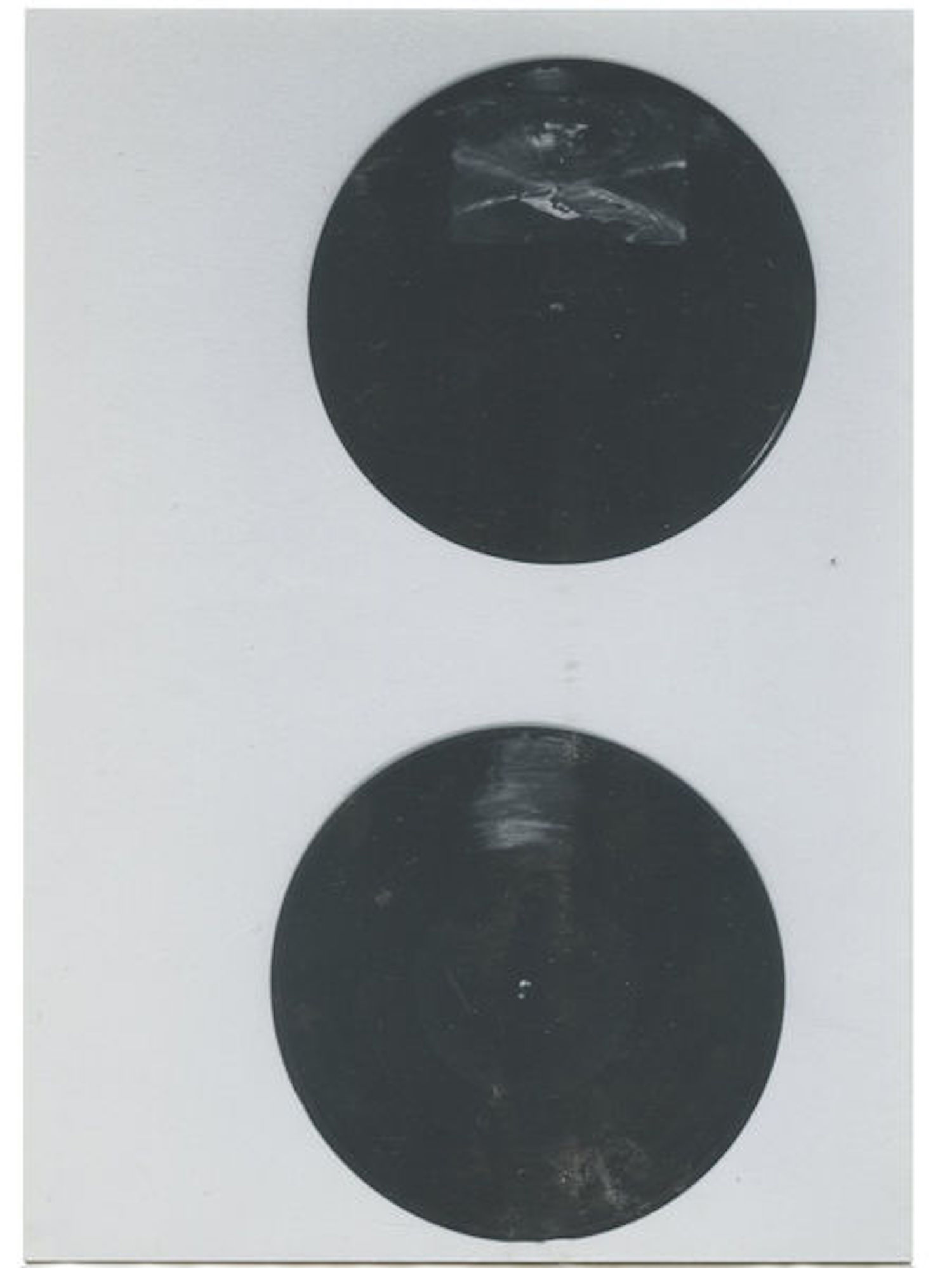 A black and white photograph of two black circles on a dark background.