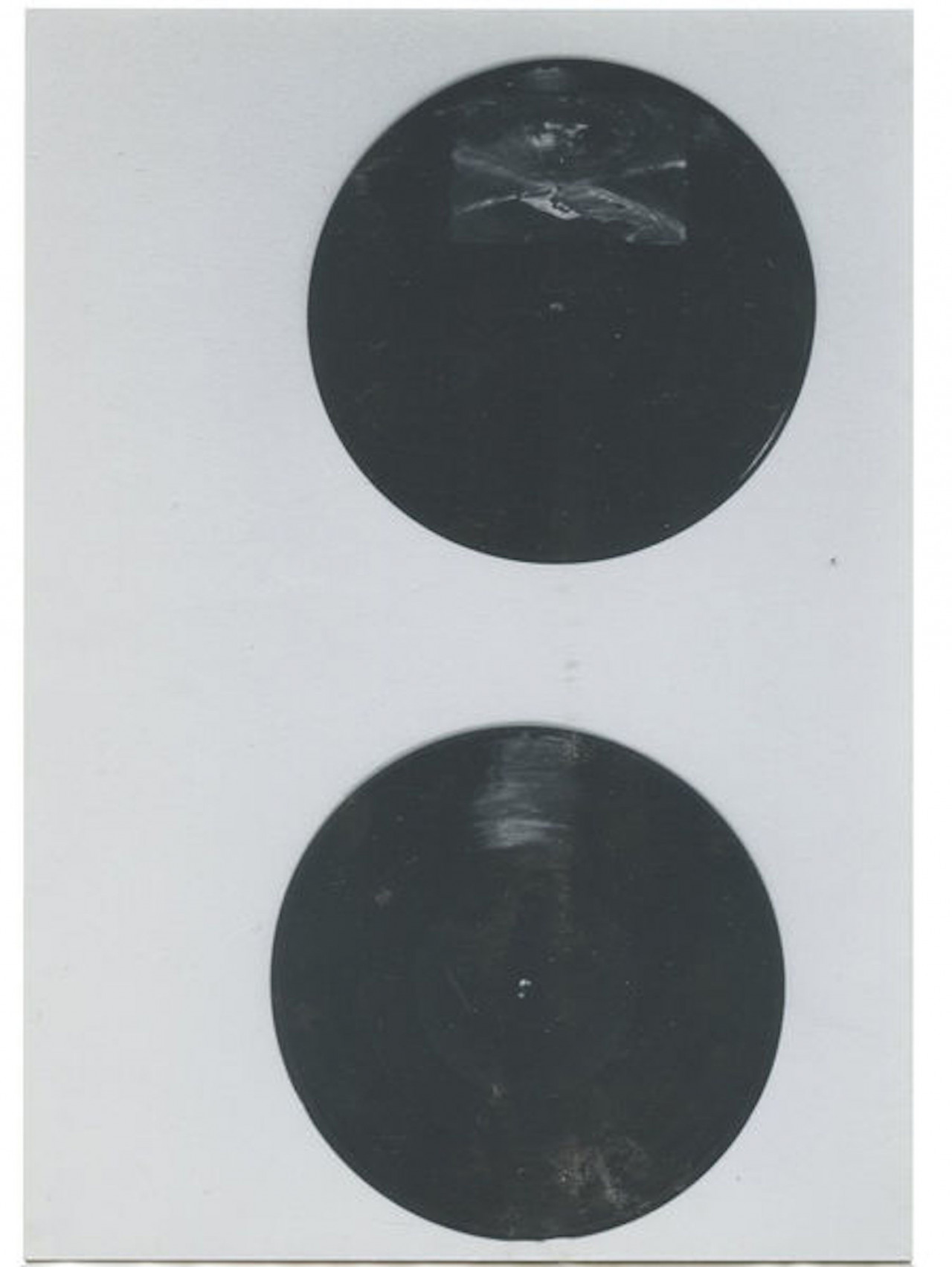 A black and white photograph of two black circles on a dark background.