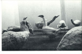 A black-and-white photograph of stuffed geese made with geese-printed fabric staged in a room.