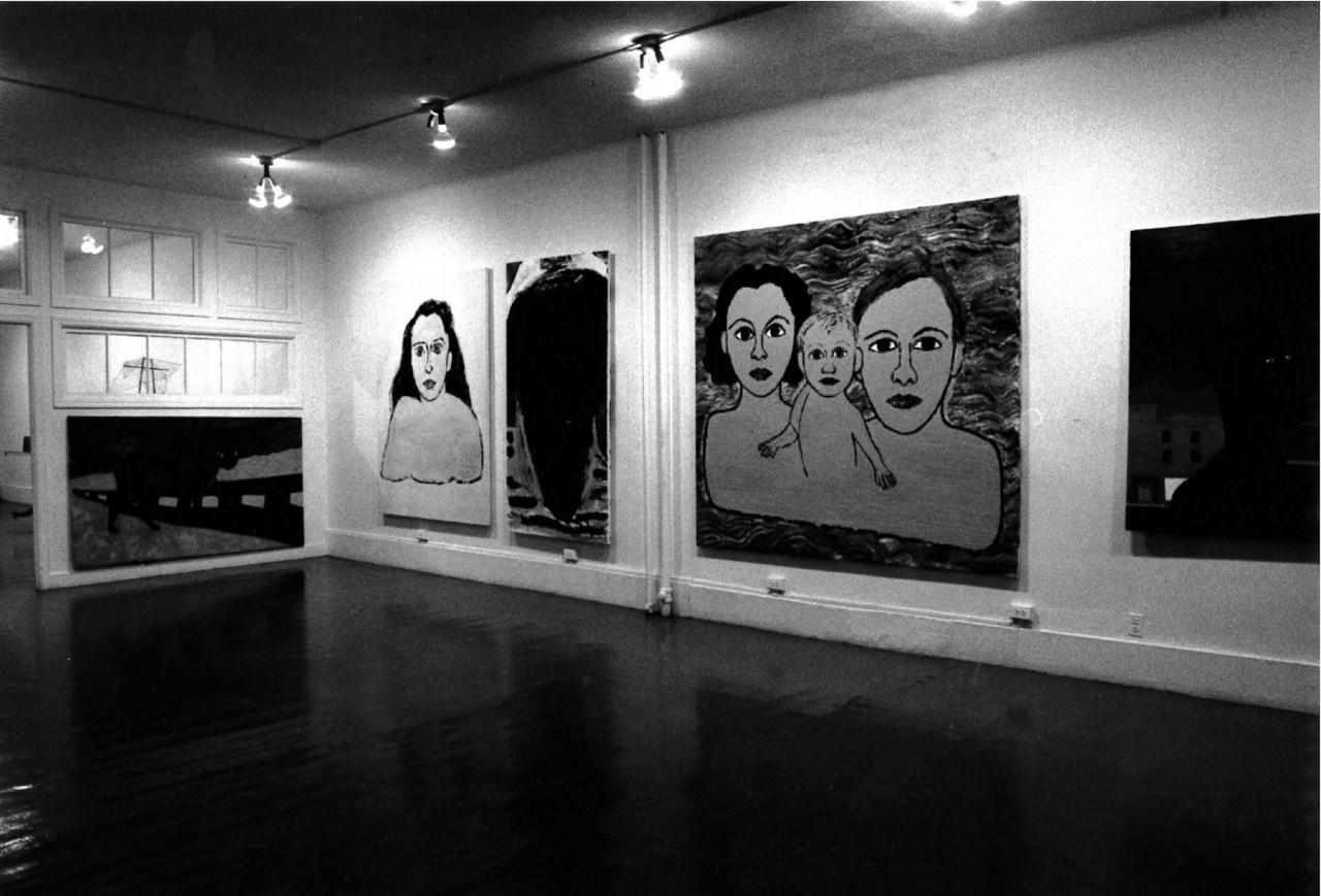 Figurative paintings hang on adjacent walls in white-walled gallery space.