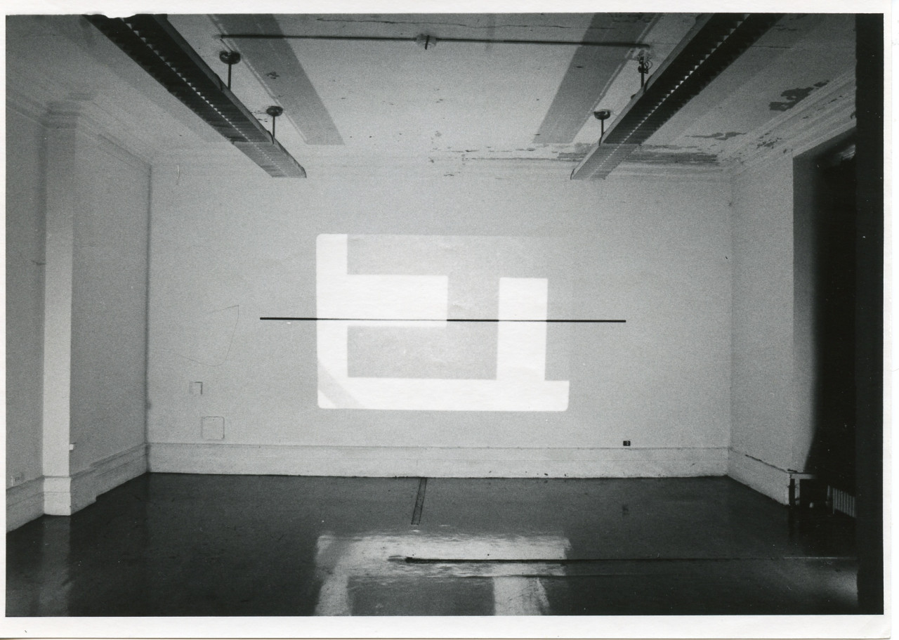 An image is projected onto a white wall. The image consists of various simple rectangular shapes.