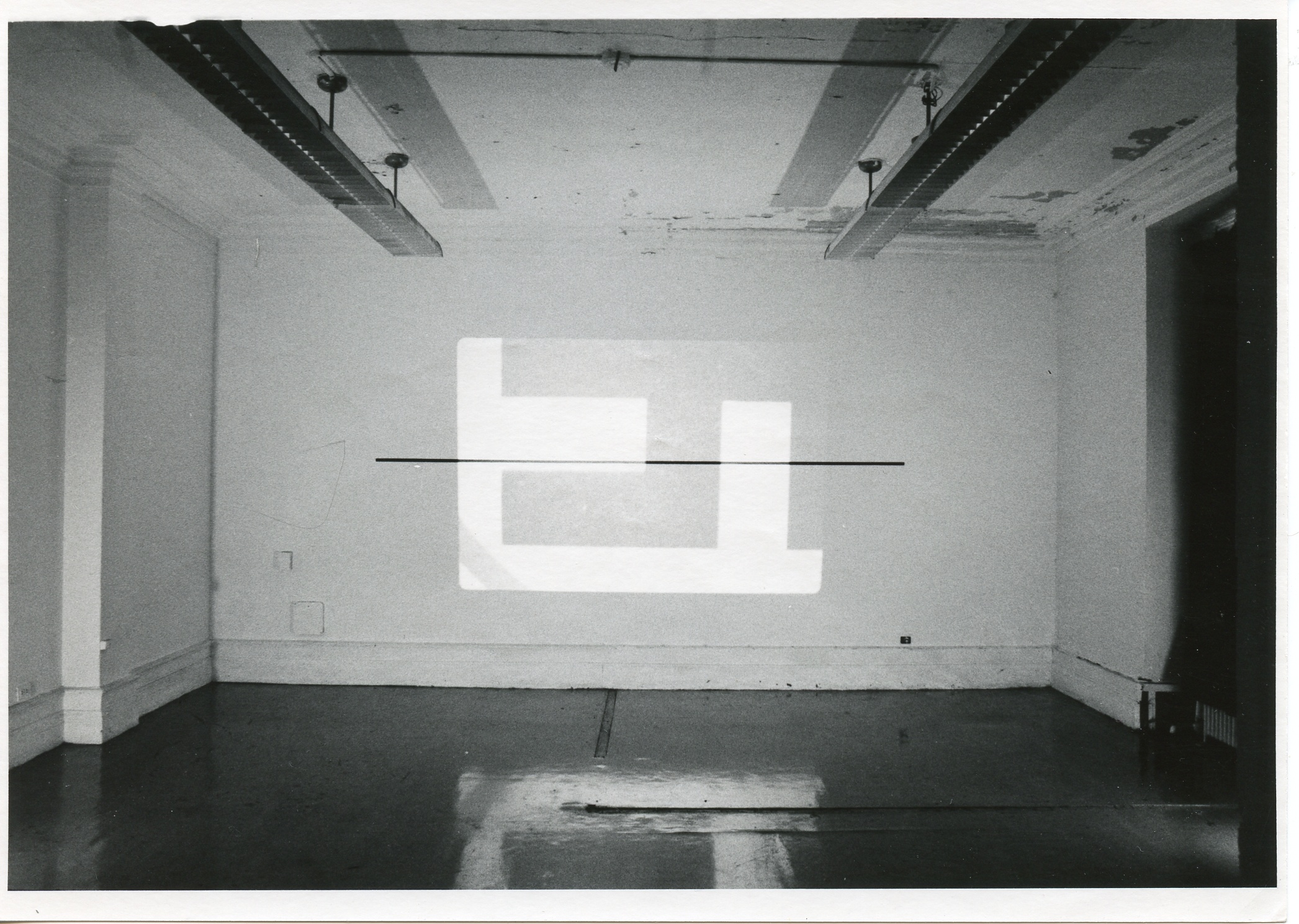 An image is projected onto a white wall. The image consists of various simple rectangular shapes.