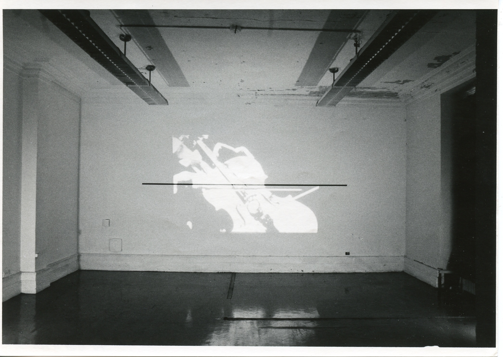 An image is projected onto a white wall. In the image, a figure plays a cello.