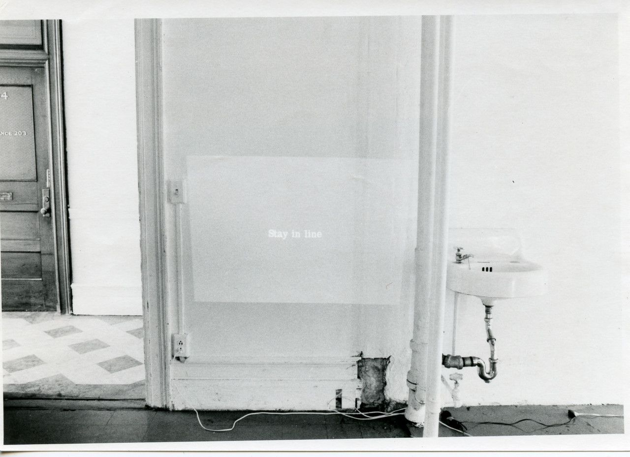 An image is projected onto a white wall. The image is text on a solid background. Text is illegible.