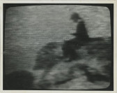 A grainy black and white image of a figure seated on an indescernible animal or object.