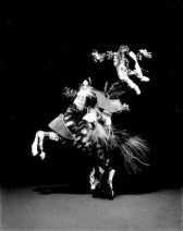 Three figures appear in distinctive dress flowing through space around each other as if in a duel amongst themselves with a black background.