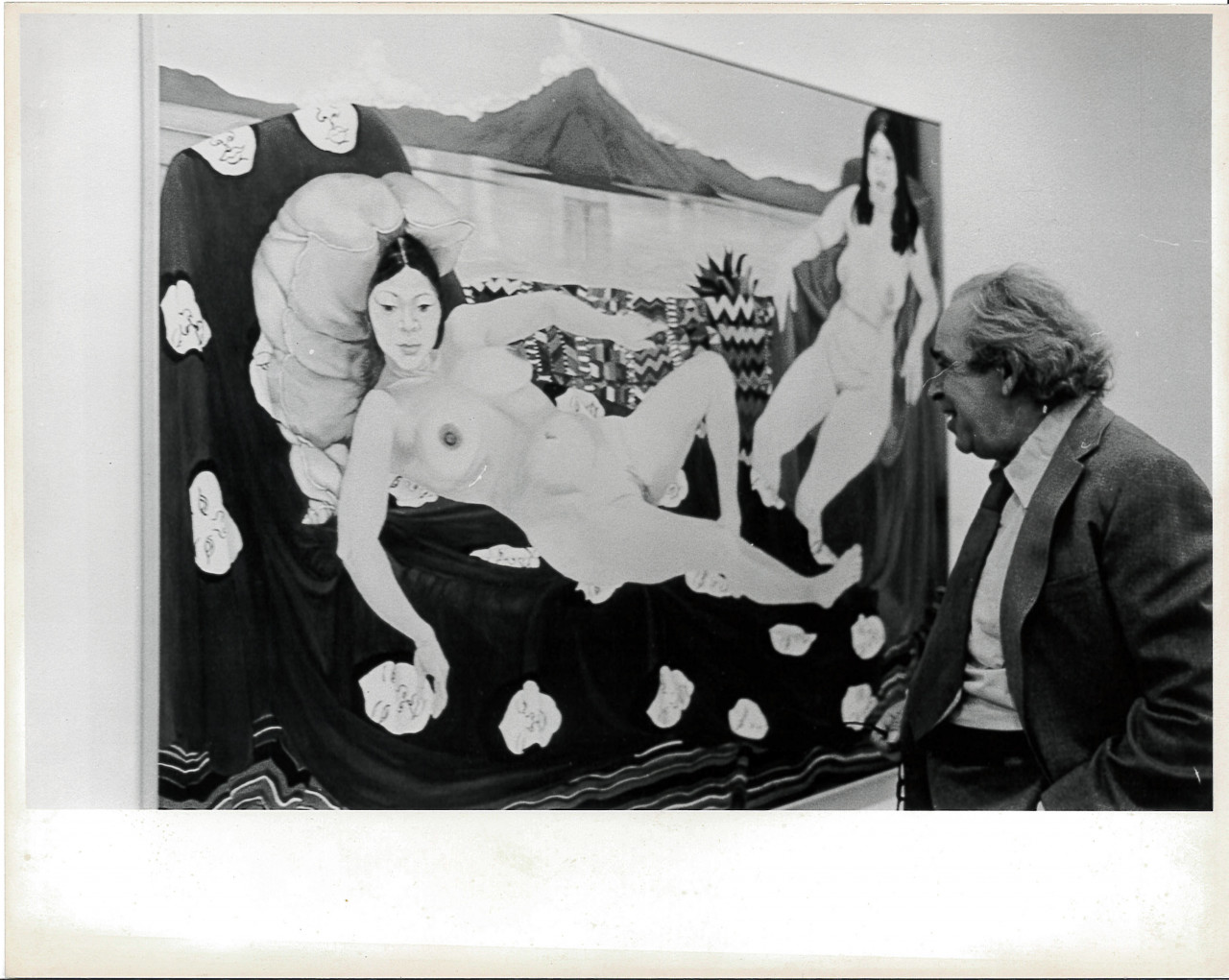 A black and white photograph of a gallery space. A painting of nude reclining women hangs on the left, and a figure in a suit and tie looks on from the right.