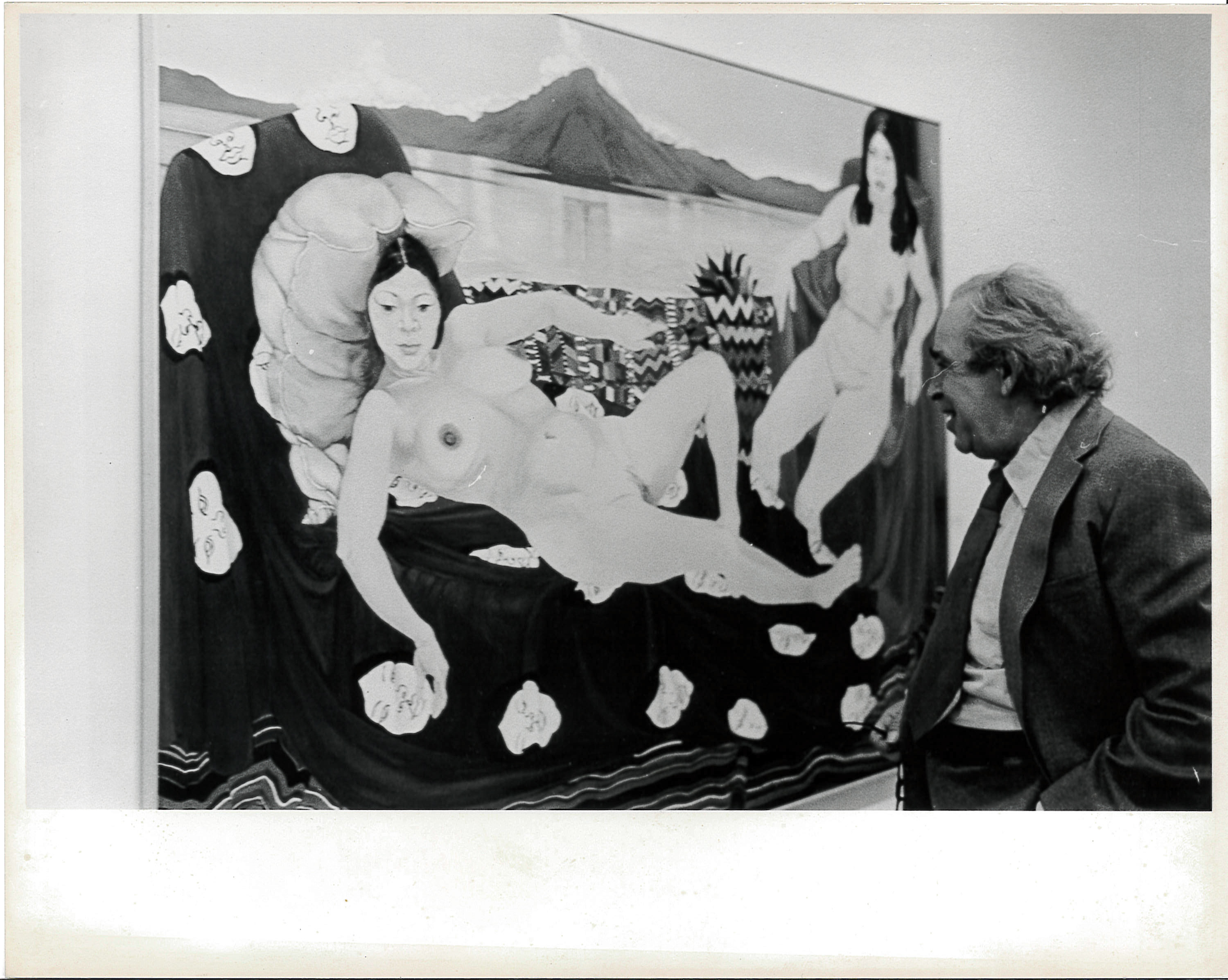 A black and white photograph of a gallery space. A painting of nude reclining women hangs on the left, and a figure in a suit and tie looks on from the right.