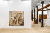 A square painting of a partially nude human figure is visible next to large, orange slug installations attached with black elastic cords onto cast iron columns.