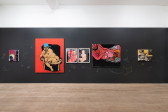 A color image of one wall of a gallery space, shot head-on. The wall is painted black, and six colorful, and intimate paintings of Black Queer figures are arranged across it. White and yellow drawings are pained onto the wall, complementing and placed around the artworks.