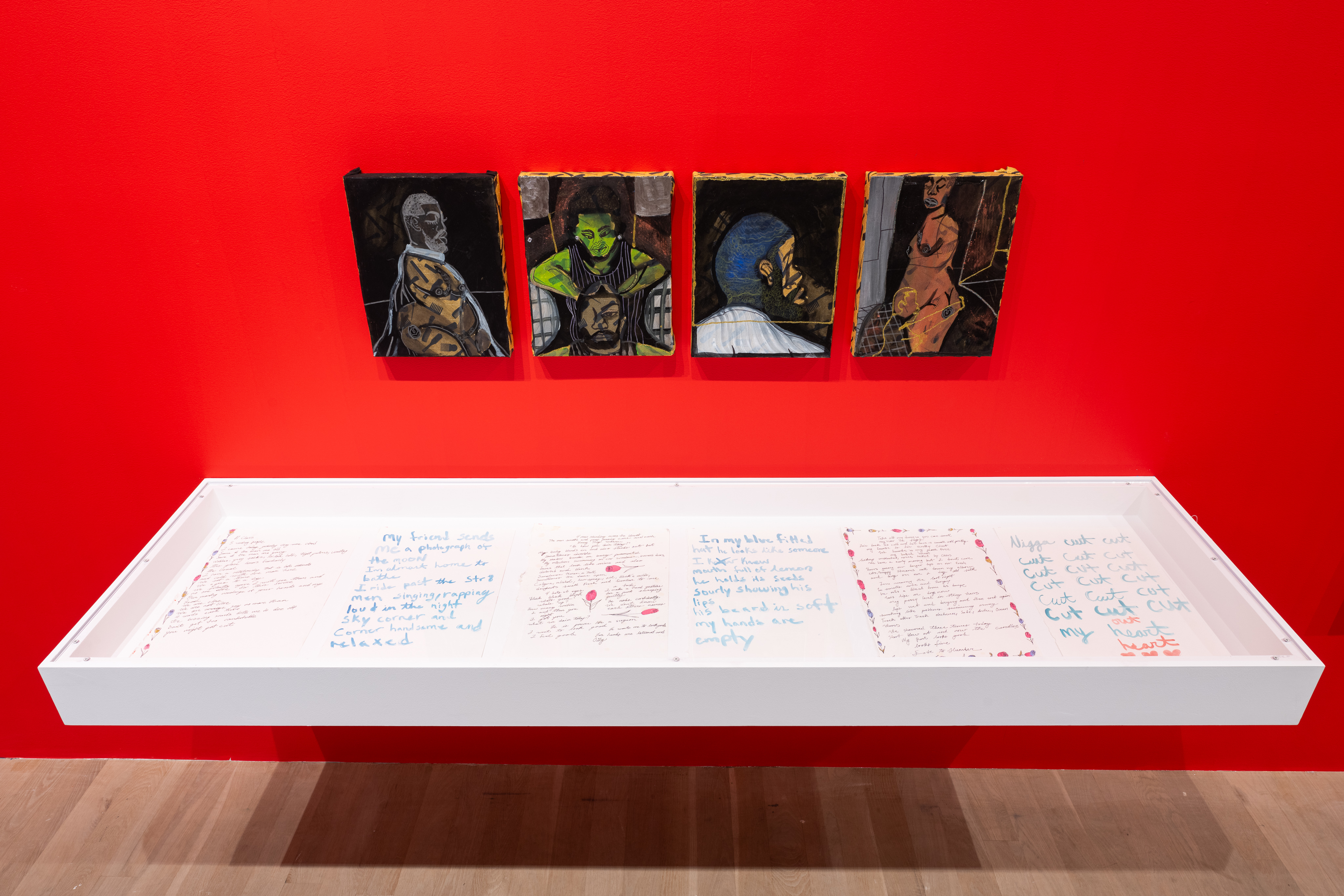 A color image of a close-up of a floating vitrine on a red wall, with four small paintings hung in a series above the vitrine. Inside the vitrine are six pages, with poems written on them and drawings of flowers decorating the pages. Thefour paintings above the poems depict Black Queer figures in darkened environments with gold, and colorful accents.