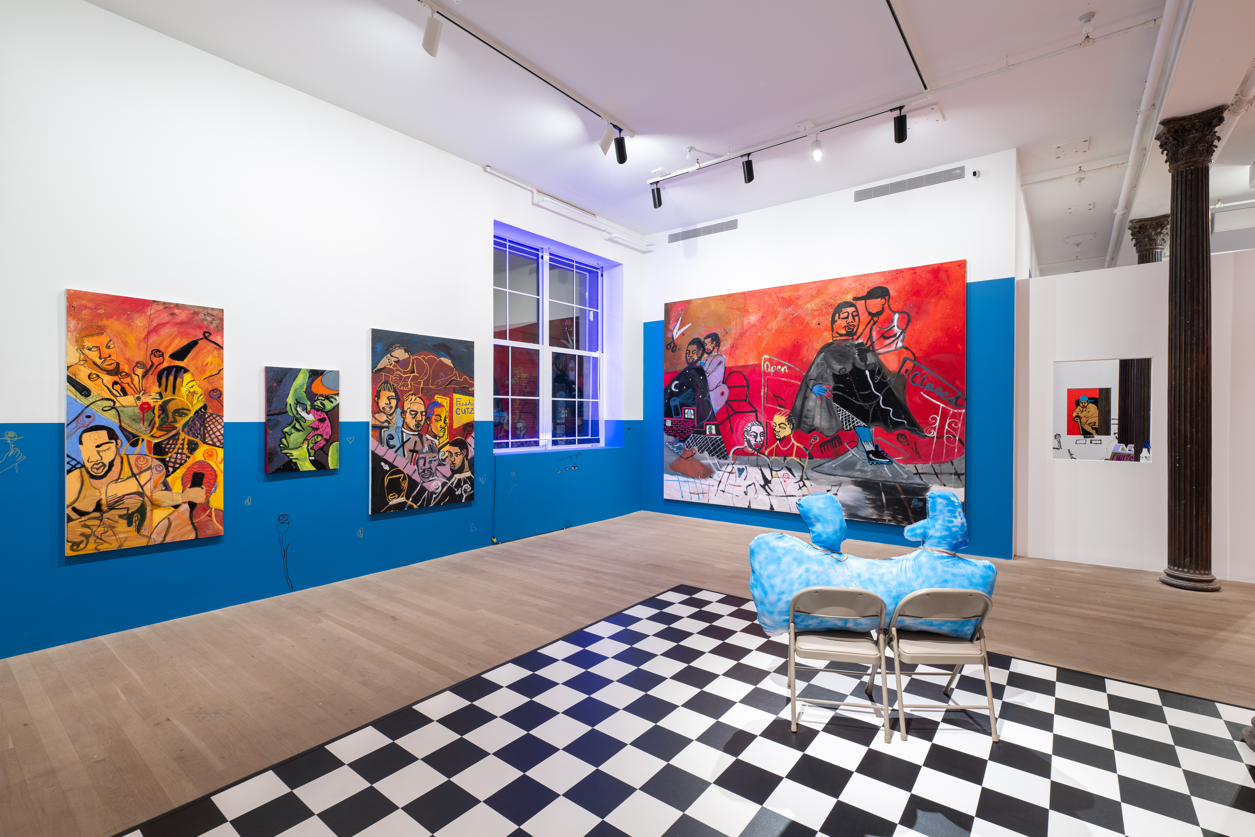 A color image of the corner of a gallery space. The walls are painted with blue accents, and there is a checkerboard floor. Large, vibrant paintings of Black Queer figures hang on the walls. Blue neon lights run along the frame of the window in the corner.