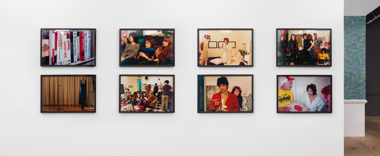 Eight, framed, color photographs arranged into a grid on a white wall.