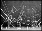 Large structures of power lines are visible with white human figures moving around in the bottom section of the image.