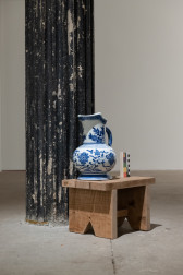A color photograph of a blye and white ceramic jug on a small wooden stool. Next to the jug is a color control strip.