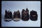 A color photograph of four sculptures resembling miniature theatre sets.