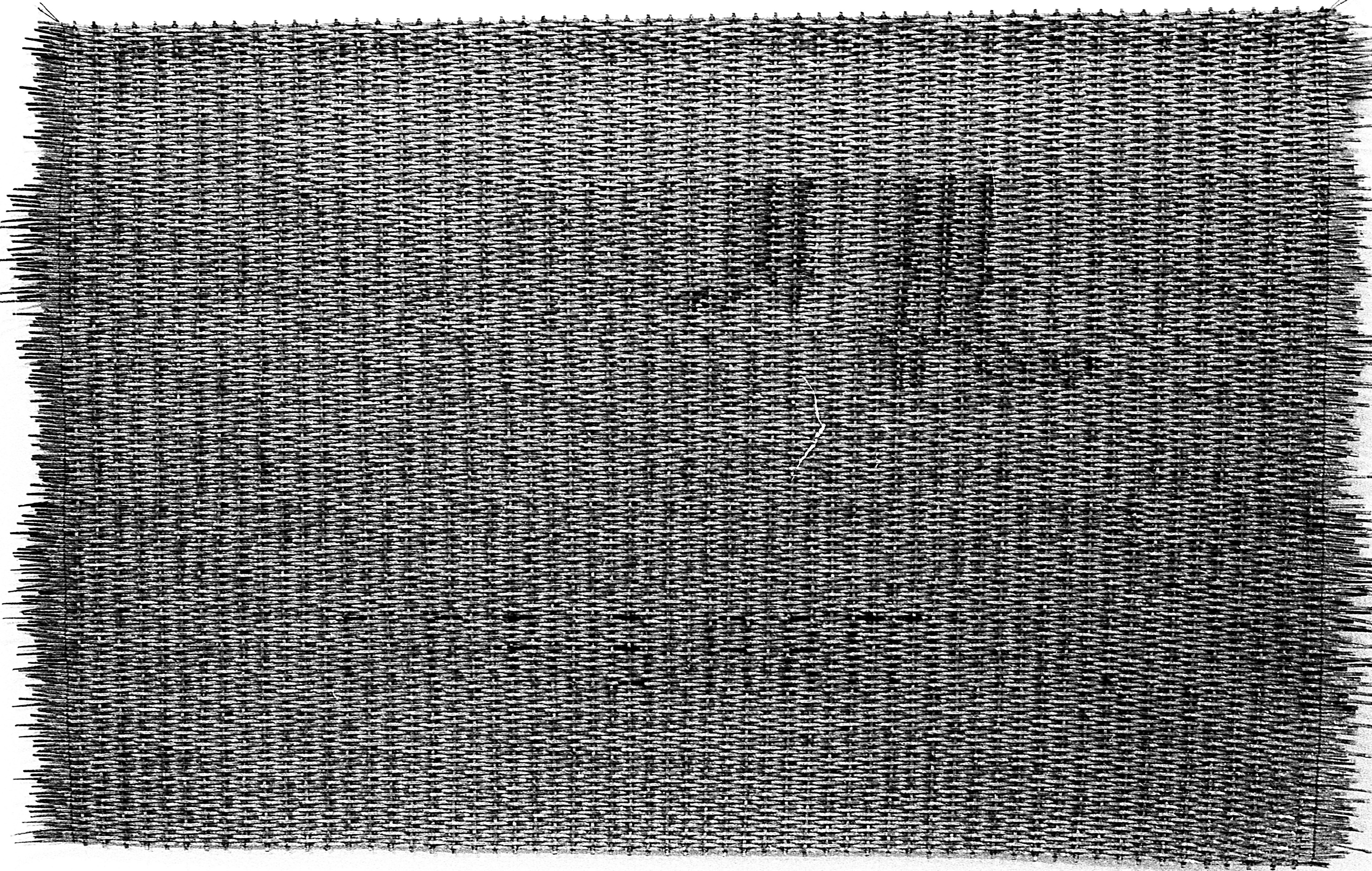 A black and white photograph of a woven mat on a white background.