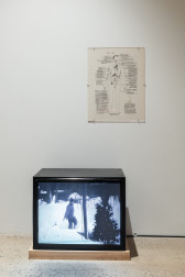 A color photograph of a floorbound television monitor, showing a figure in a snow bank. Above is an annotated drawing of a human figure.