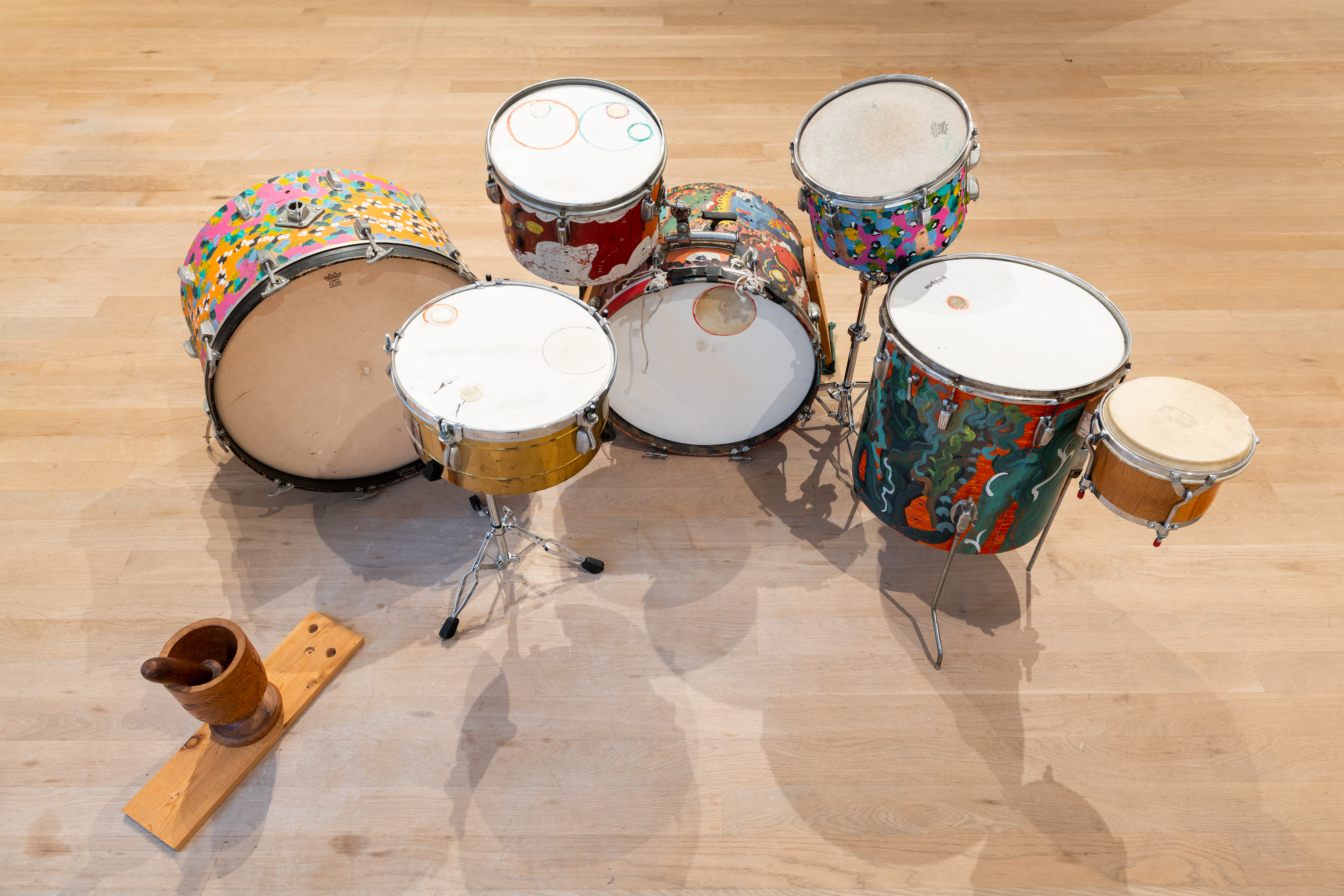 An aerial view of a hand painted drumset on a wooden floor.